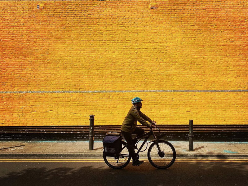 A man is riding a bicycle in front of a gold coloured wall